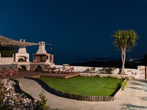 Une terrasse sur le toit avec des sièges extérieurs, un petit jardin et une vue sur la mer au crépuscule.