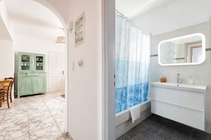 Bathroom features a large mirror, sink, and shower area with a patterned curtain.