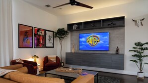 A modern living room with a flat-screen TV, red sofas, a coffee table, and a plant. - Space City - Prof. Design, Game Room, King BD (Houston)