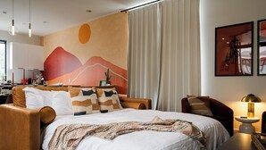 A modern hotel room with a large bed, a desk, a chair, and a dining area. - Space City - Prof. Design, Game Room, King BD (Houston)