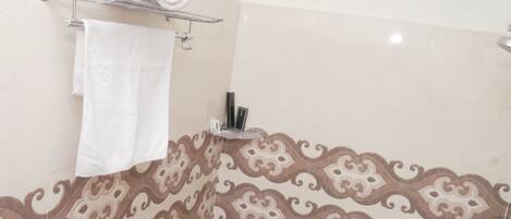 A bathroom with a patterned tile design, a towel rack with rolled towels, and a mirror.