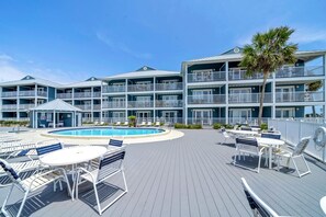 A multi-story hotel with a pool, outdoor seating, and a palm tree.