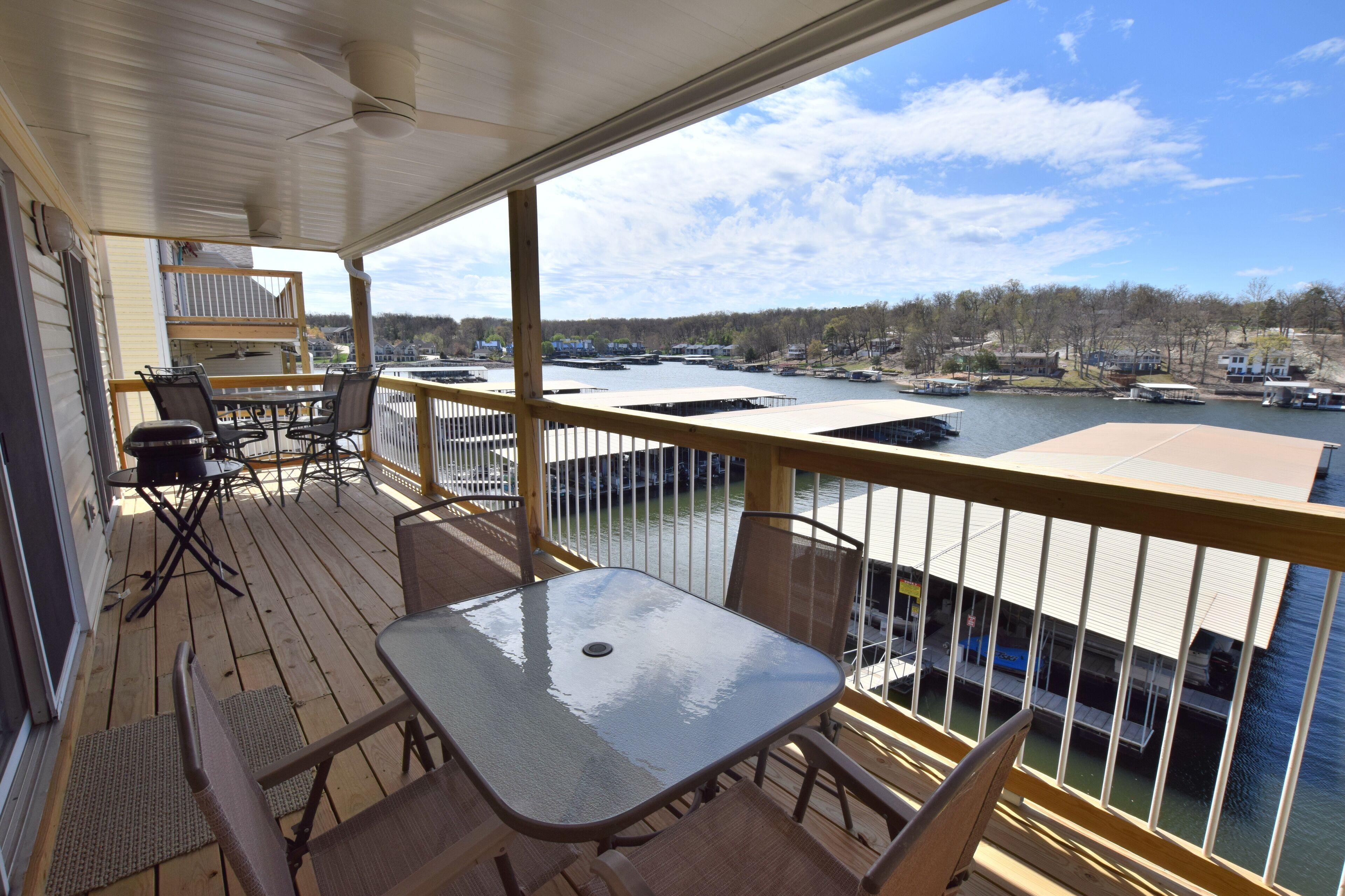 Una terraza techada al aire libre con una mesa y sillas, con vista a una marina con barcos y un lago.