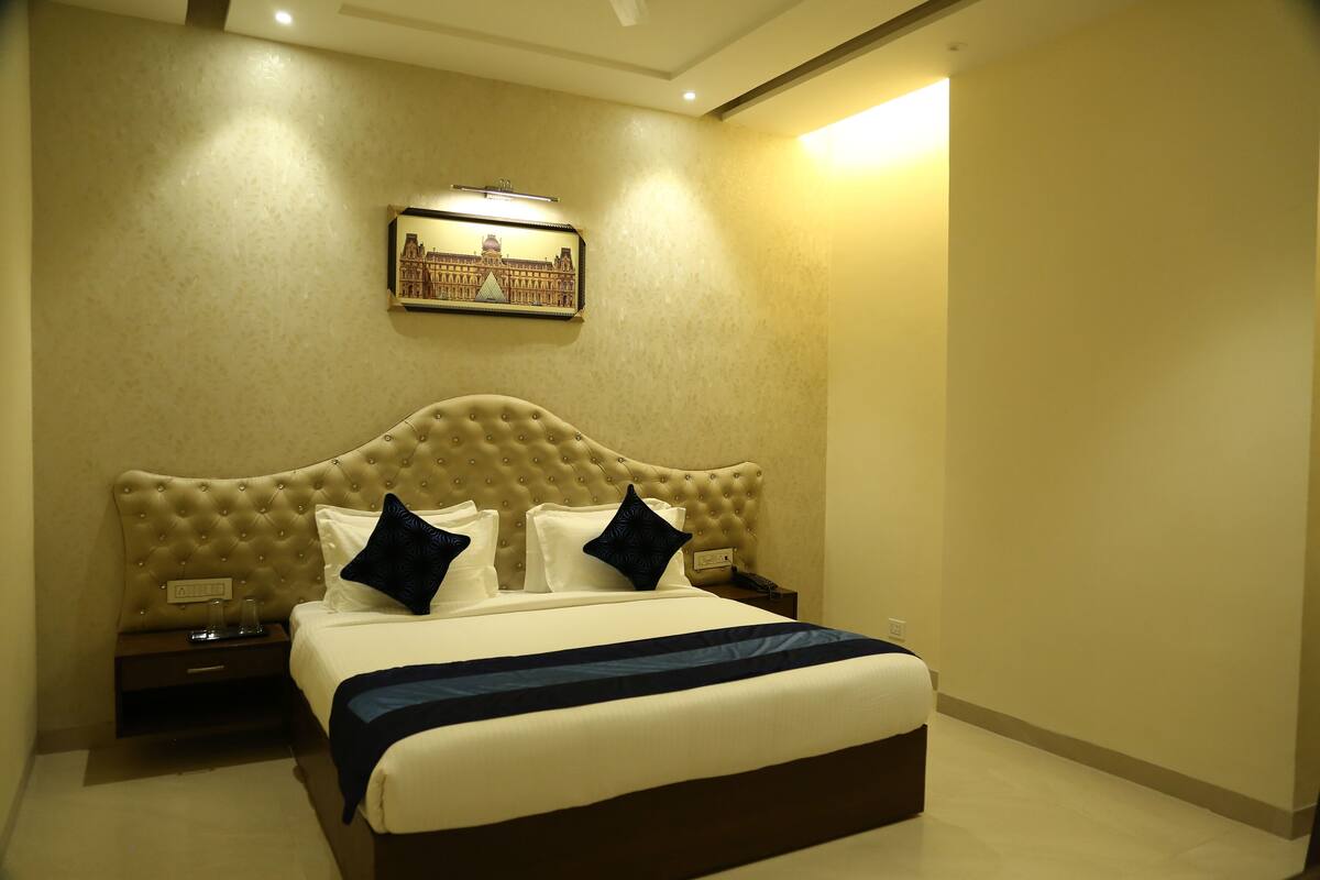 A hotel room with a large bed, a headboard with a tufted design, two bedside tables, and a framed picture on the wall.