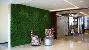 A lobby with a green wall, two patterned armchairs, a small round table, and a sign reading "Spice". - Hotel Blue Sapphire (Dera Bassi)