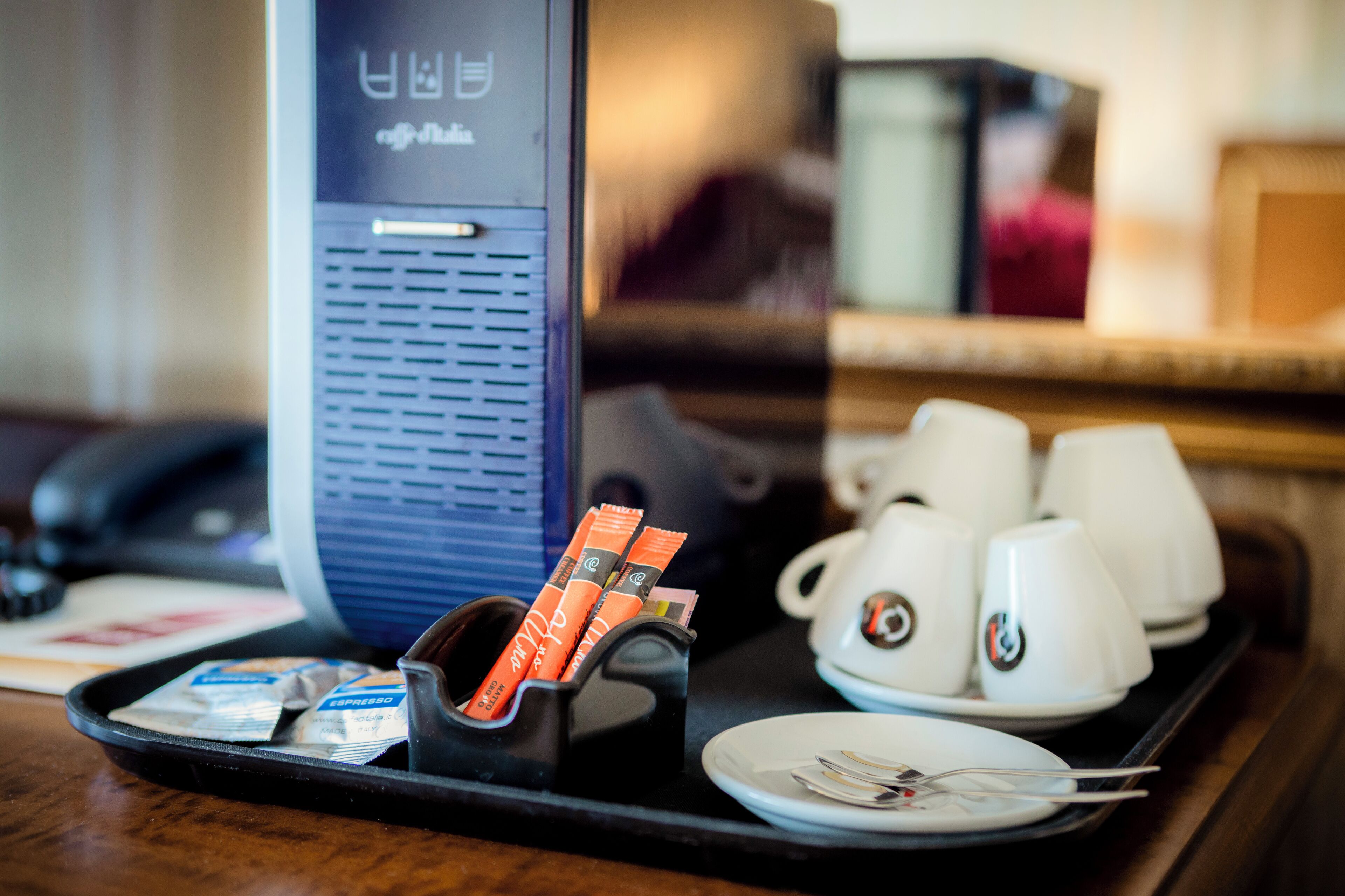 A tray with coffee cups, a phone, and a coffee machine.