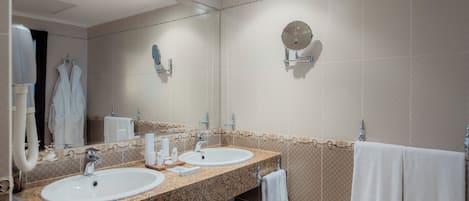 A hotel bathroom with two sinks, a large mirror, and a towel rack.