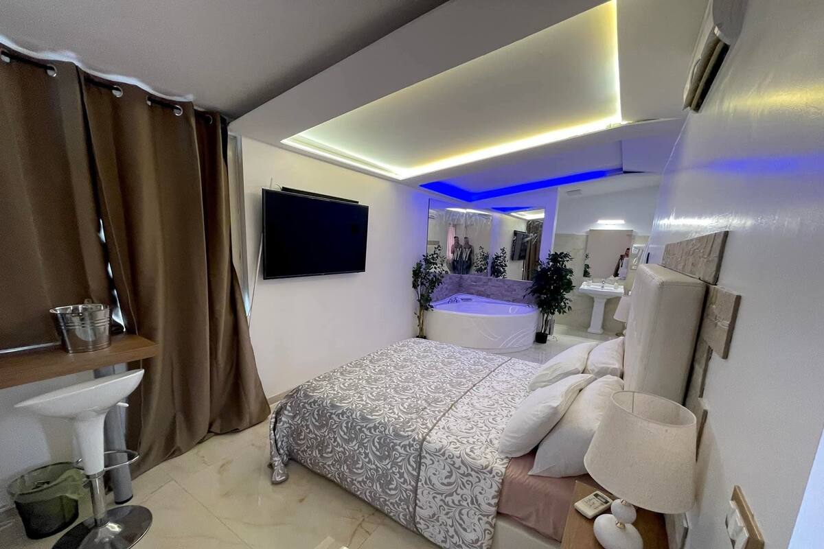 Un dormitorio moderno con cama, mesita de noche y un espejo grande.