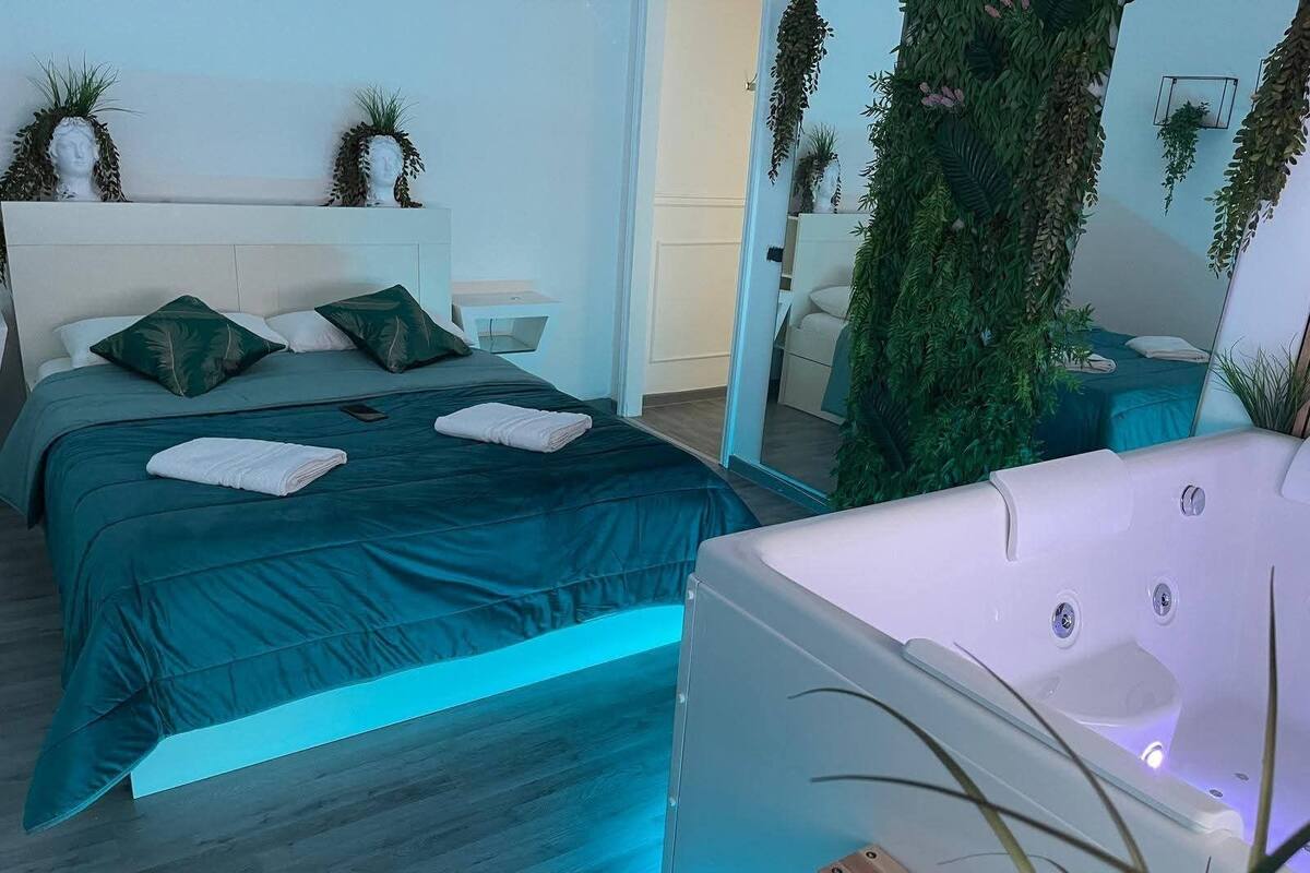Un dormitorio moderno con una cama grande, una sala de estar independiente y un jacuzzi.