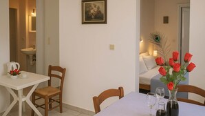 Ein Essbereich mit Tisch für zwei Personen, einem Stuhl, einer Vase mit roten Rosen und einem Bild an der Wand.