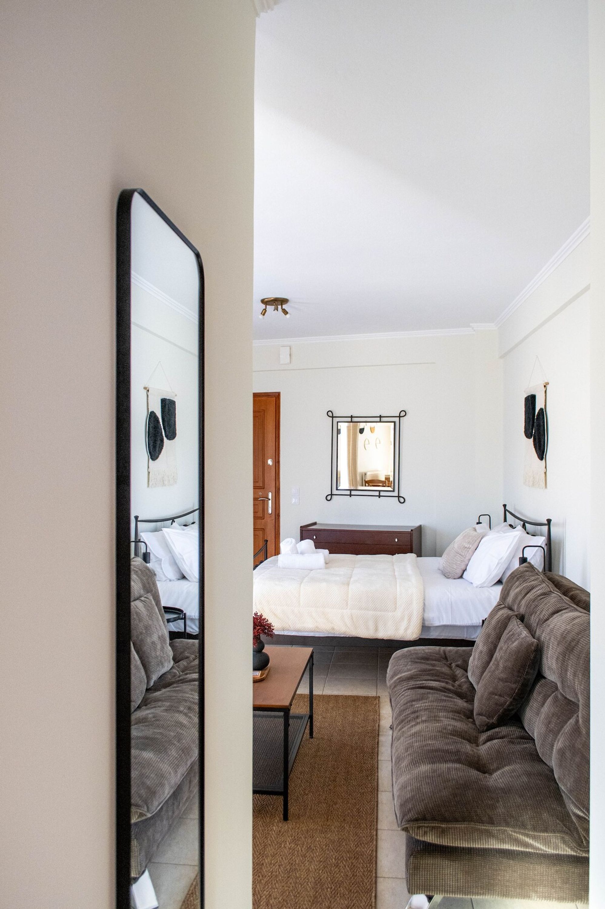 A bedroom with a bed, two sofas, a small table, and a mirror.