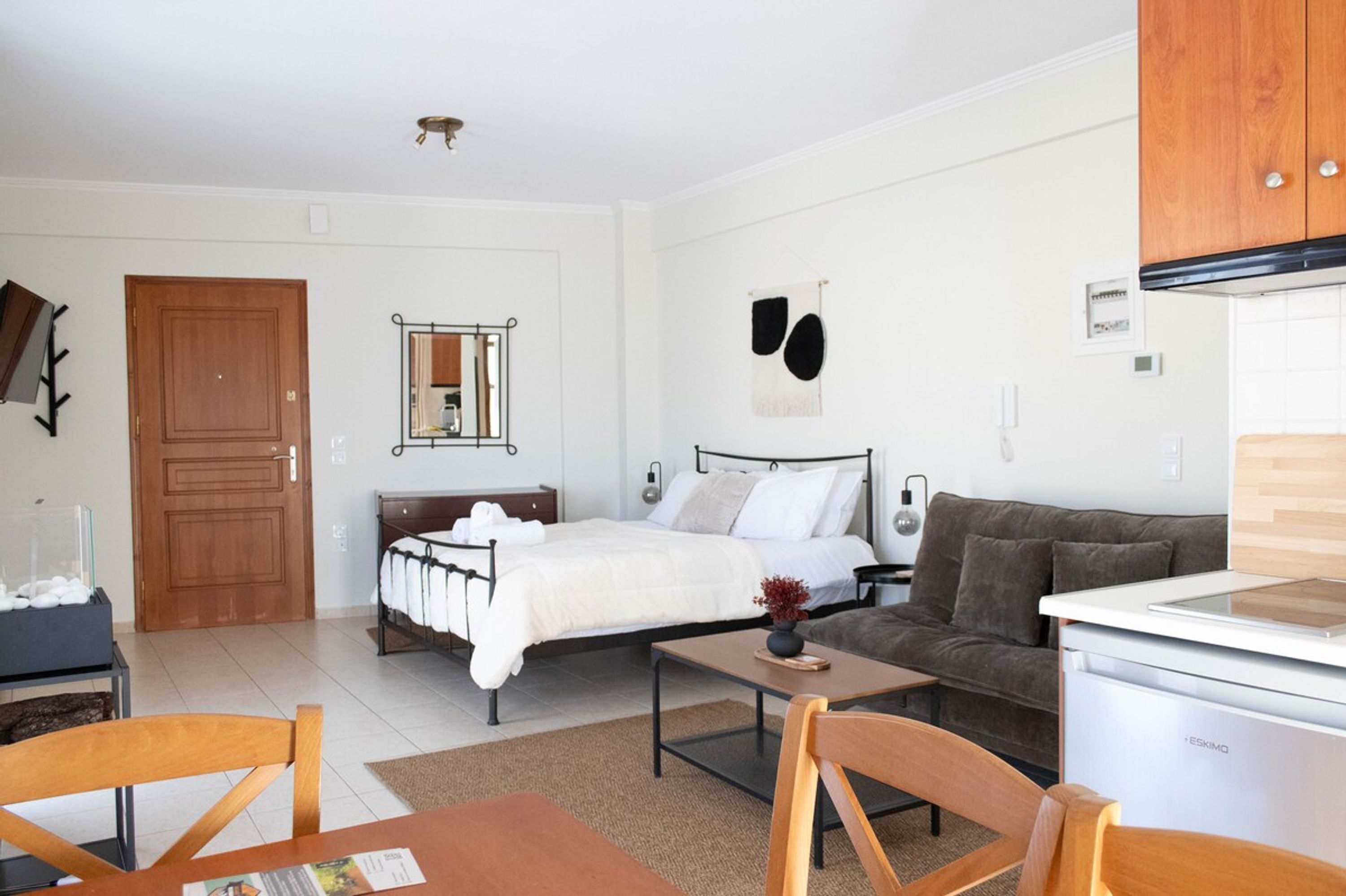 A modern bedroom with a bed, bedside table, and a small kitchenette.