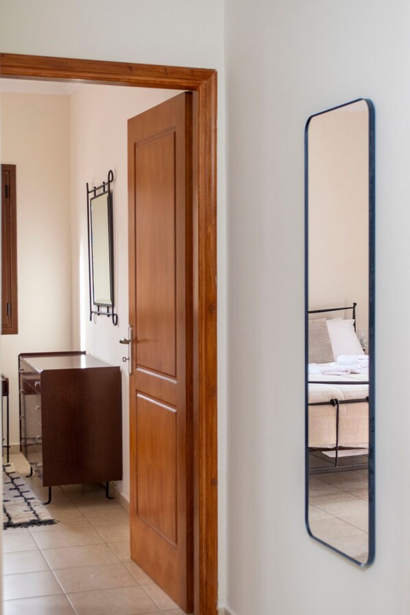 A bedroom with a bed, a bedside table, and a mirror on the wall. - Rokani Studio I at Kalavrita Center (Kalavrita)