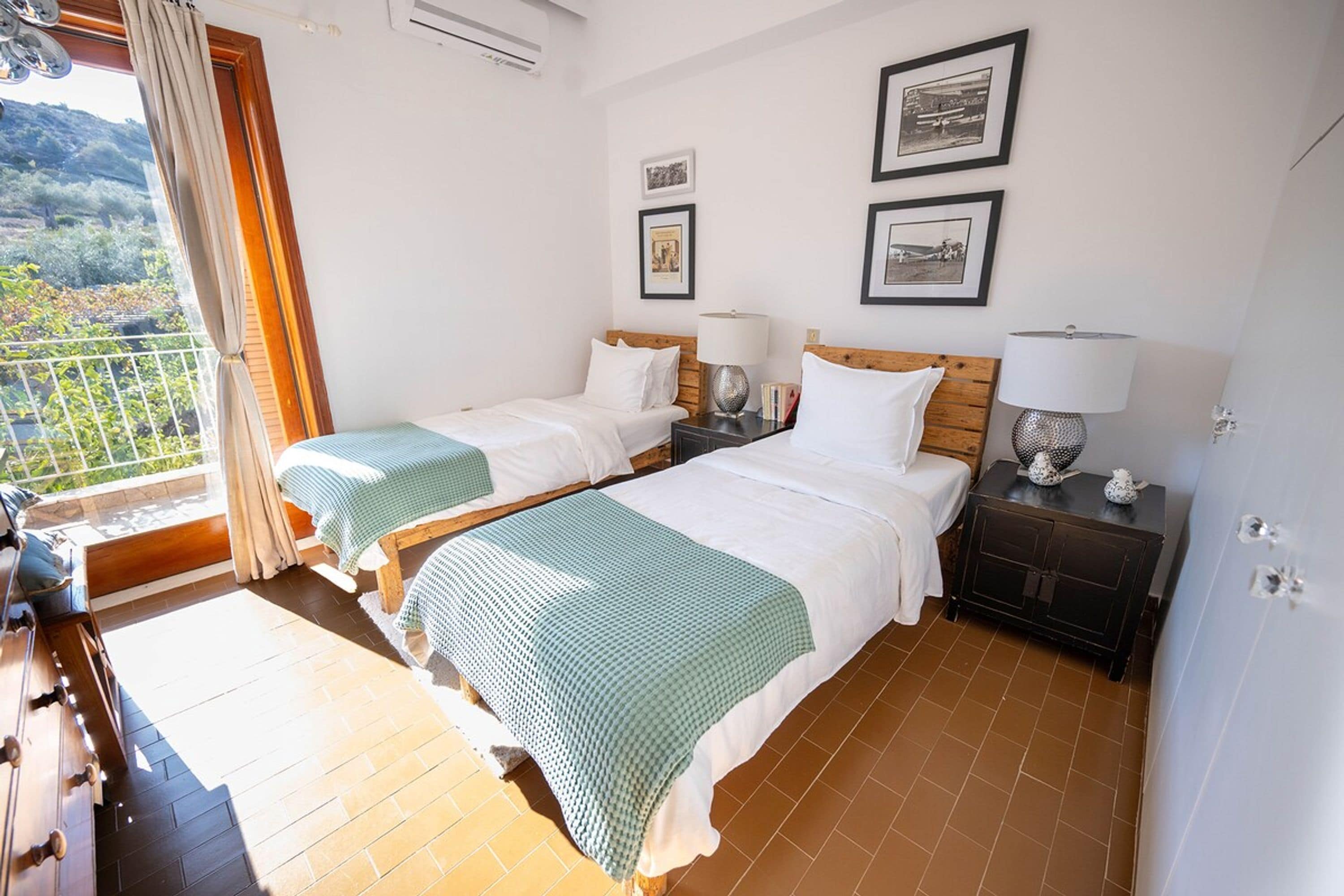Een hotelkamer met twee bedden, een balkon en uitzicht op de omgeving.