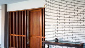 Ein Zimmer mit einer Holztür, einer weißen Ziegelwand und einem dunklen Holztisch.