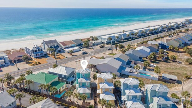 A coastal residential area with houses, a beach, and a road.