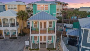 A coastal residential area with multiple houses, including a prominent two-story house with a balcony and a porch.