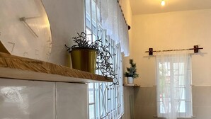 A kitchen with a stainless steel sink, a window with decorative metal grilles, and a small potted plant on the counter. - Hibiscus Cove (Sandy Bay)