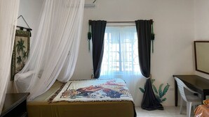 A bedroom with a bed, a desk, and a window with curtains. - Hibiscus Cove (Sandy Bay)