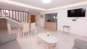Un salon moderne comprenant un coin repas, une cuisine et un escalier.