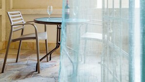 En balkon med et bord, to stole, en vinflaske og et glas.