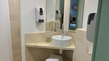 A modern bathroom with a white sink, a mirror, a toilet, and a shelf with folded towels.