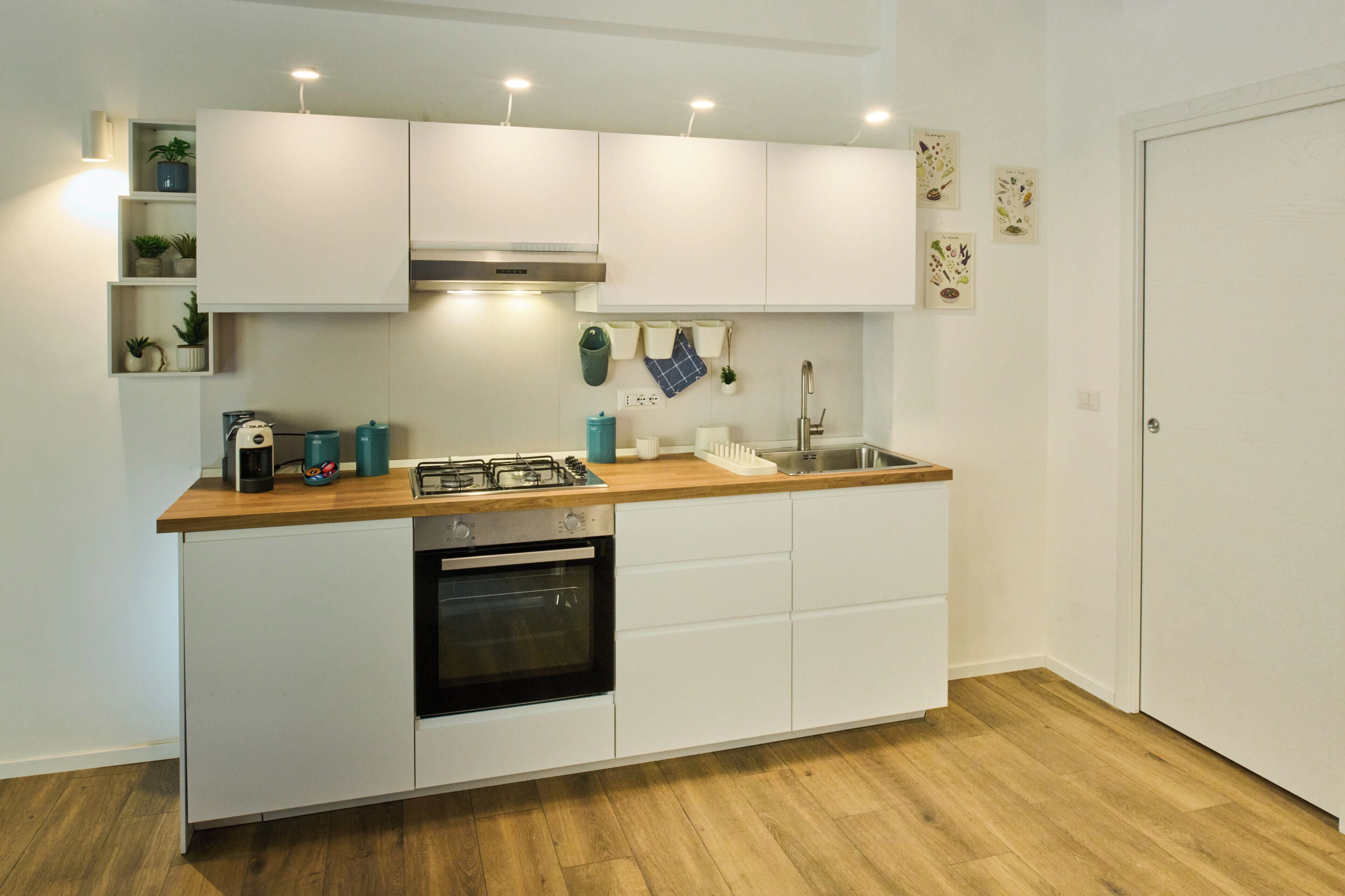 Eine moderne Küche mit weißen Schränken, einer Holz Arbeitsplatte, einem eingebauten Backofen und einem Spülbecken.