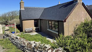 A stone house with a dark roof, a chimney, and a sign reading 'WITHI-GILL'. - Withi-gill - Bay of Ireland Views 50m From Beach (Stromness)