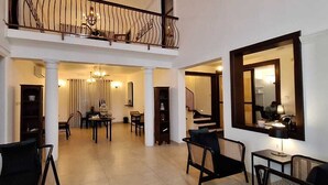 Amplia sala de estar con techo alto, balcón y comedor con candelabro.