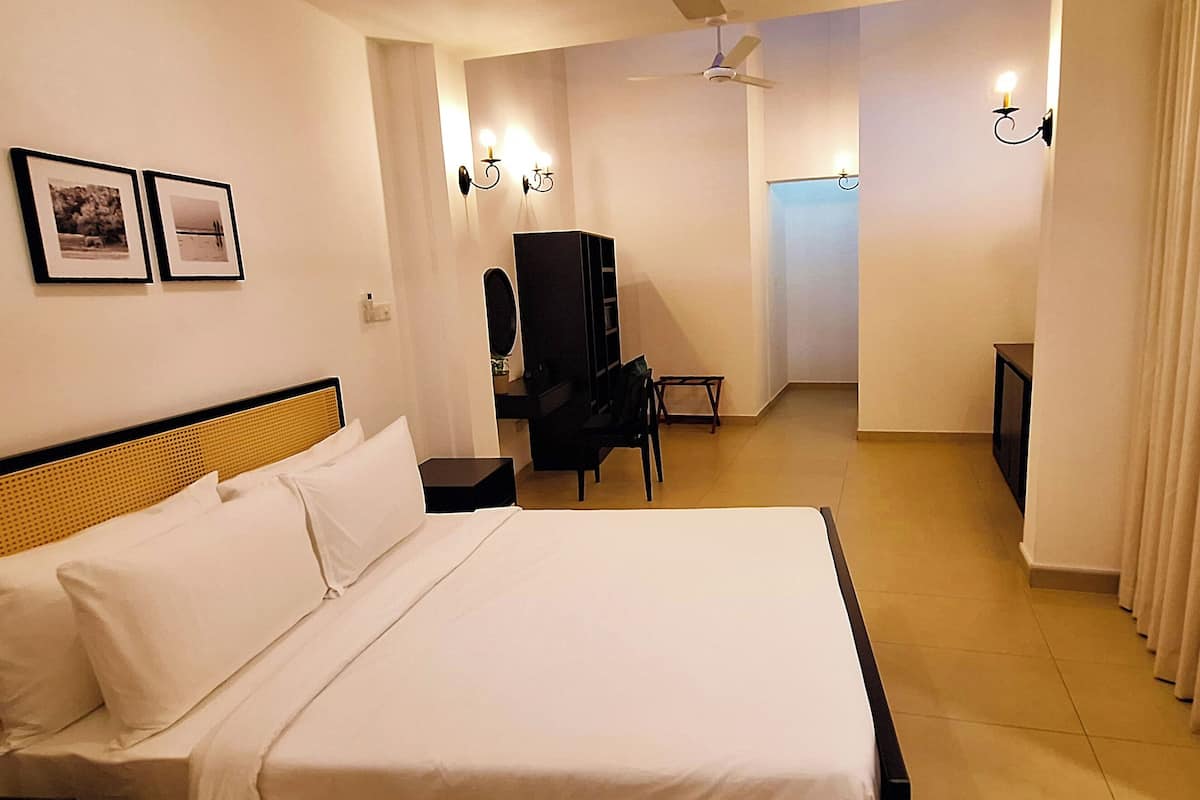 Una habitación de hotel con una cama grande, un escritorio, una silla y un televisor.