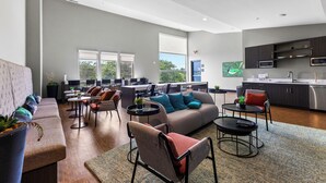 A spacious living area with a sofa, chairs, a coffee table, and a kitchen area with cabinets and a sink. - Cozy Nautical Themed 2-bedroom condo with AC in charming Traverse City. (Traverse City)