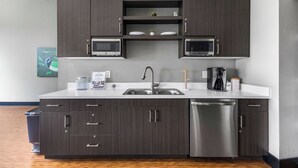 A modern kitchen with dark wood cabinets, a stainless steel dishwasher, and a microwave. - Cozy Nautical Themed 2-bedroom condo with AC in charming Traverse City. (Traverse City)