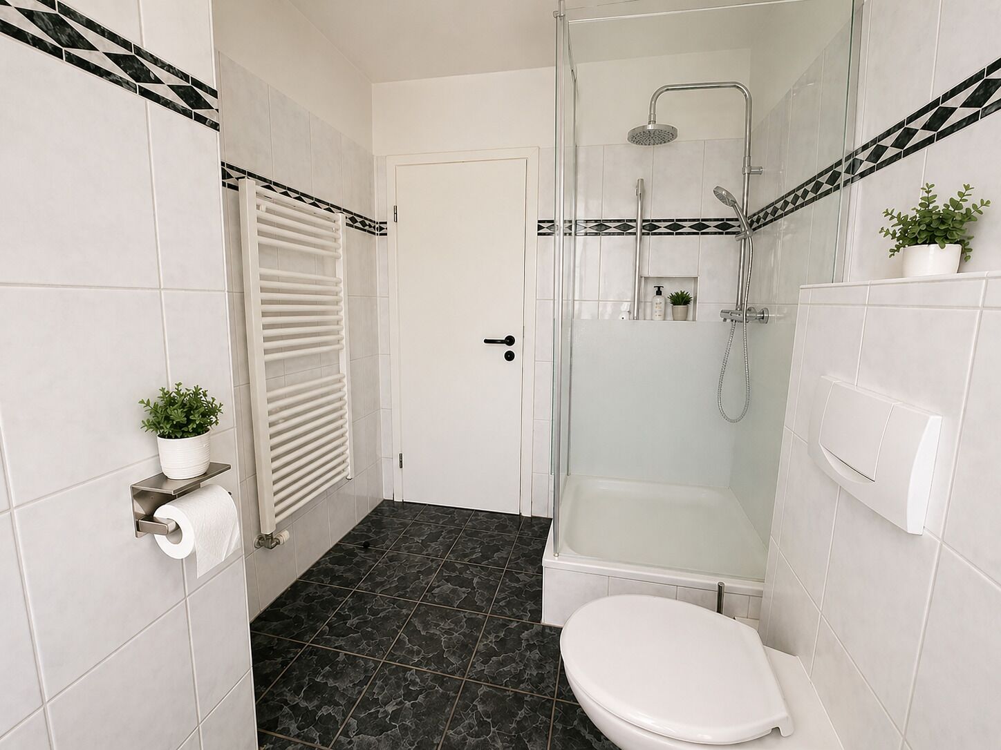 A bathroom with a shower, toilet, and a towel rack.