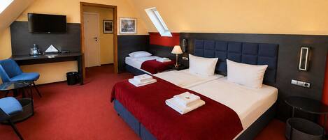 A hotel room with a bed, a desk, a chair, a TV, and a window.