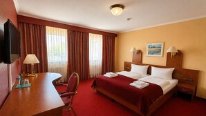 Une chambre d’hôtel comprenant un lit, des tables de chevet, un bureau avec une lampe, une chaise et un téléviseur.