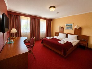 A hotel room with a bed, bedside tables, a desk with a lamp, a chair, and a television. - Hotel Schwarzenbek (Schwarzenbek)