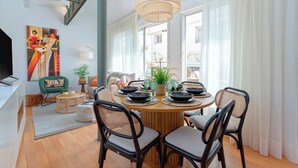 A dining area with a round table, black chairs, and a hanging light fixture.