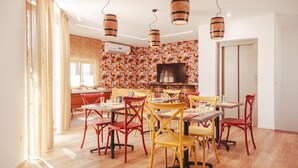 A dining area with wooden flooring, red and yellow chairs, and a patterned wall. - U Zuccareddu (Alcamo)