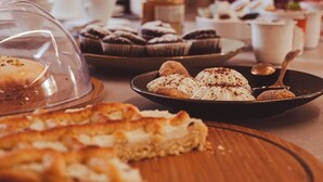 A variety of desserts on a table, including a covered pastry, a plate with cupcakes, and a bowl with a dessert topped with chocolate shavings. - U Zuccareddu (Alcamo)