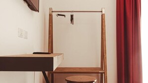 A room with a wooden desk, a wooden chair, a wooden stool, a wooden bed frame, a red curtain, and a television mounted on the wall. - U Zuccareddu (Alcamo)
