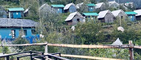 A rural village with traditional houses, bamboo fences, and a clear view of the surrounding hills.