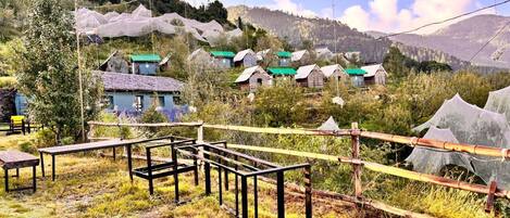 A rural village with traditional houses, a bamboo fence, and a clear view of the surrounding hills.