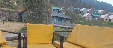 A rustic outdoor seating area with yellow chairs and a campfire.