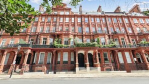 A red brick townhouse with a symmetrical facade, multiple windows, and a central entrance. - Elegant 3-Bedroom Luxury Retreat in Prestigious Cadogan Square (London)