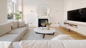 A modern living room with a sofa, a coffee table, a fireplace, and a television. - Elegant 3-Bedroom Luxury Retreat in Prestigious Cadogan Square (London)