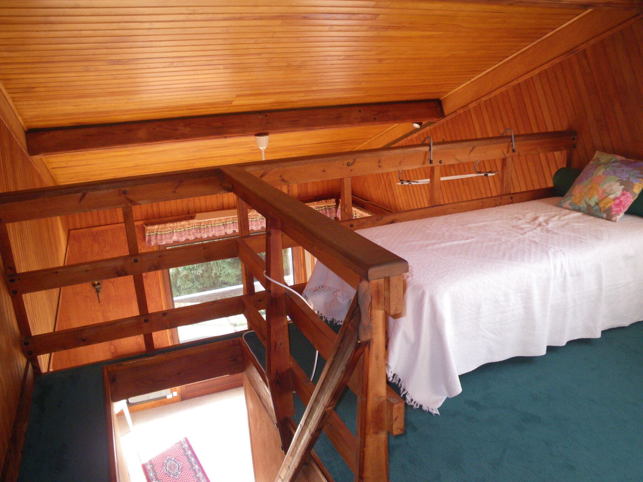 A wooden cabin with a loft bed, a small window, and a wooden staircase.
