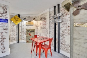 Unique room design features a brick wall with a whiteboard, a red table, and street signs.
