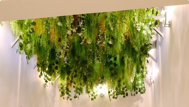 A lobby with a green hanging plant installation, a wooden sculpture, and a door labeled 'XIII'. - THE ATRIUM LAGOS (Lagos)