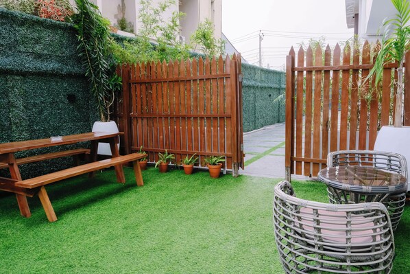A patio with a wooden bench, wicker chairs, and a table. - THE ATRIUM LAGOS (Lagos)