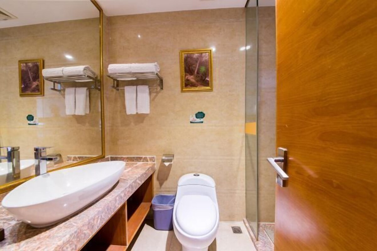 Un bany modern amb un gran mànec oval, un vàter i una cabina de dutxa de vidre.